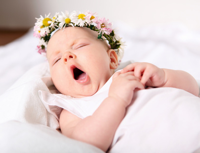 Un bébé qui baille dans un lit après avoir consulté un ostéopathe